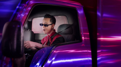 a man in a red shirt driving a purple truck