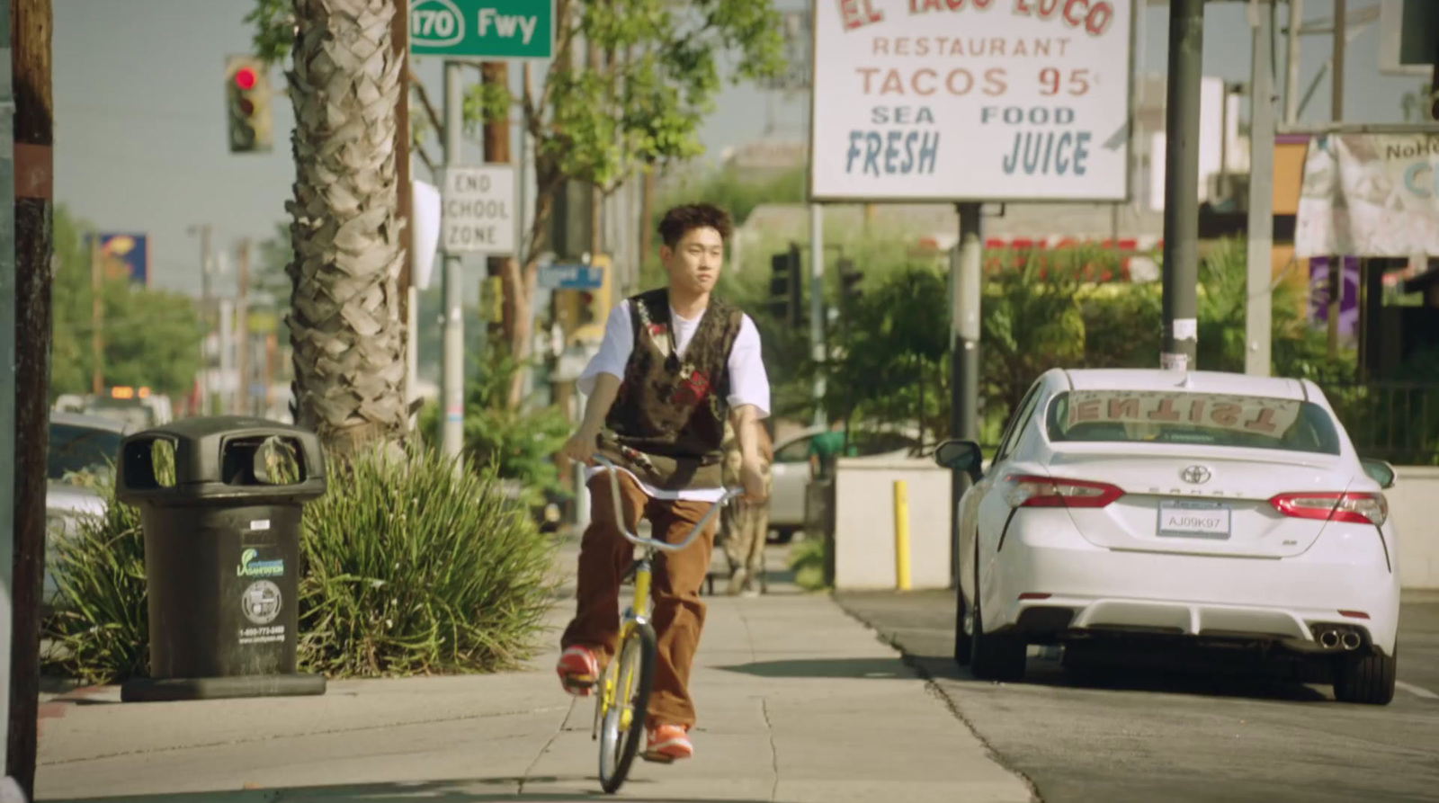 a man riding a bike down a street next to a white car