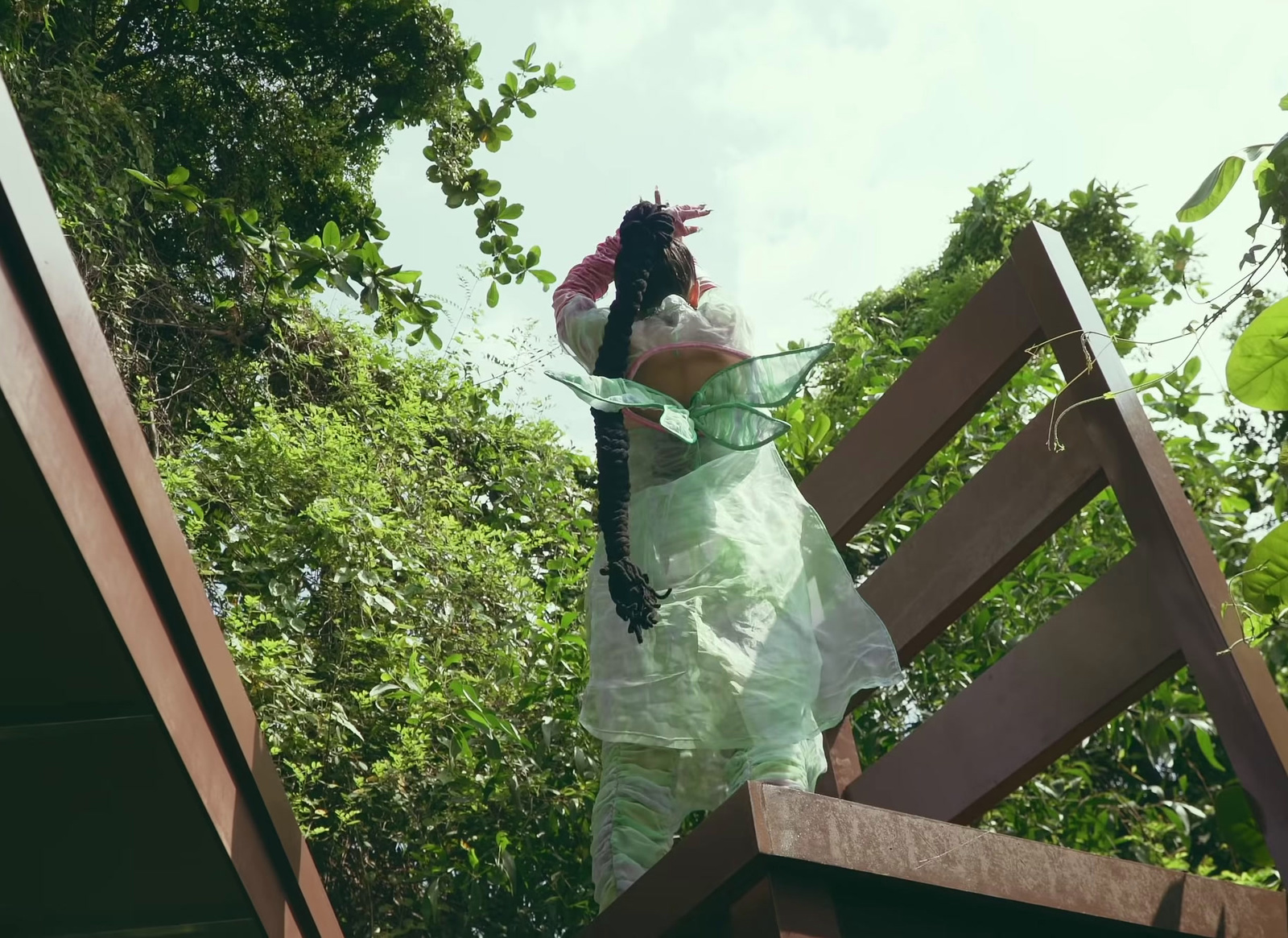 a woman in a green dress standing on a wooden staircase