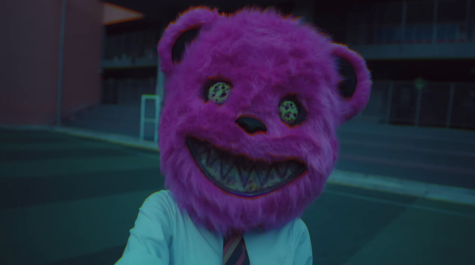 a man in a tie and a purple teddy bear mask