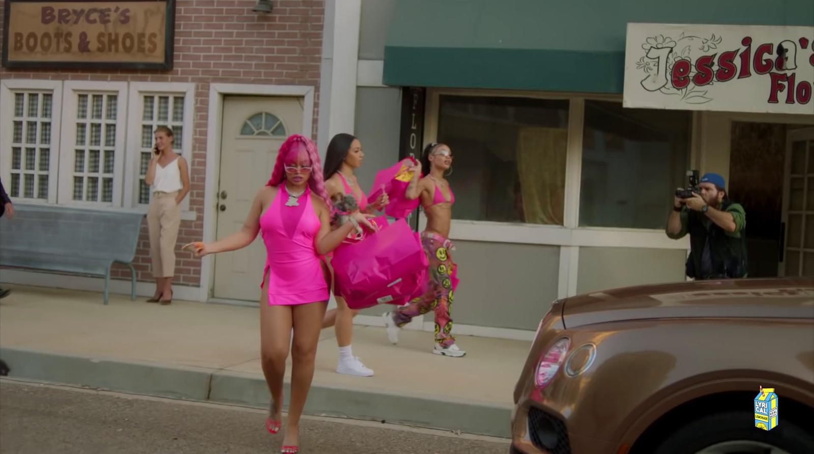 a group of women in pink dresses walking down a street