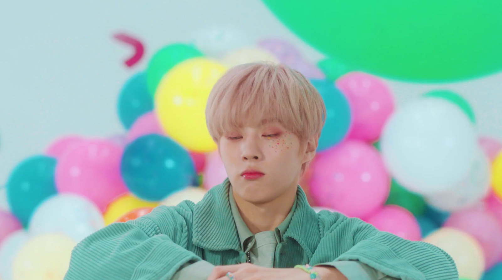 a young man sitting in front of a bunch of balloons