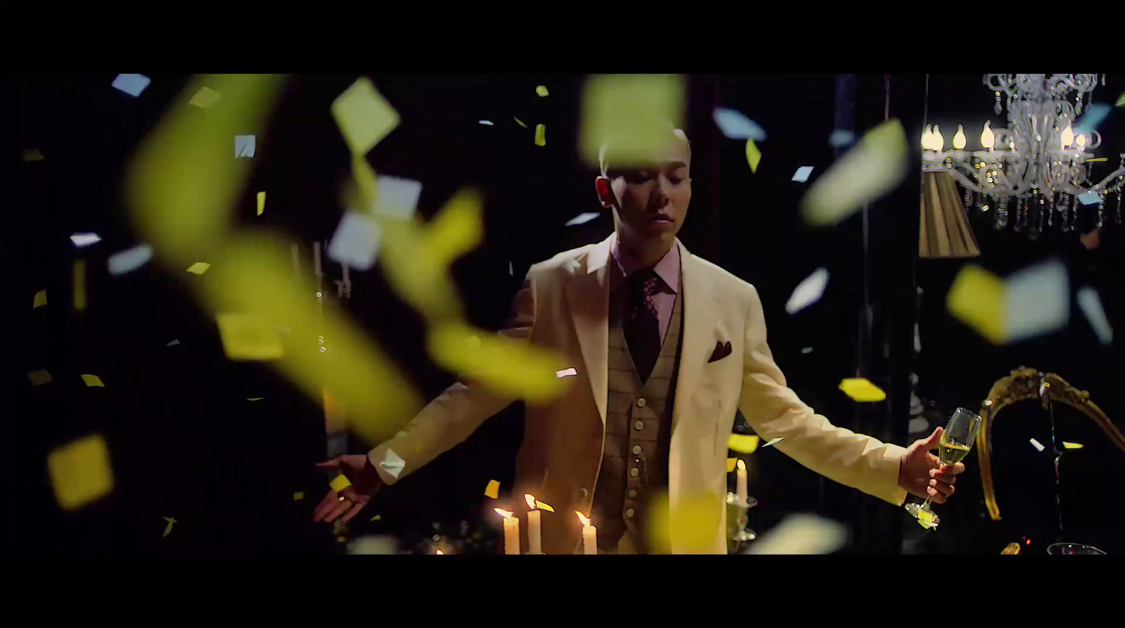 a man in a suit and tie standing in front of a chandelier