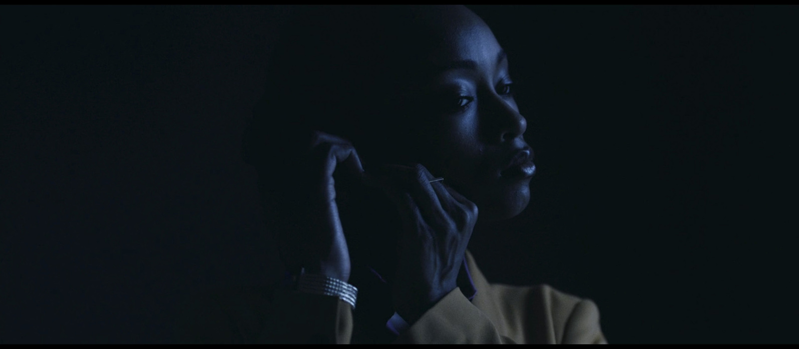 a woman in a dark room holding her hand up to her face