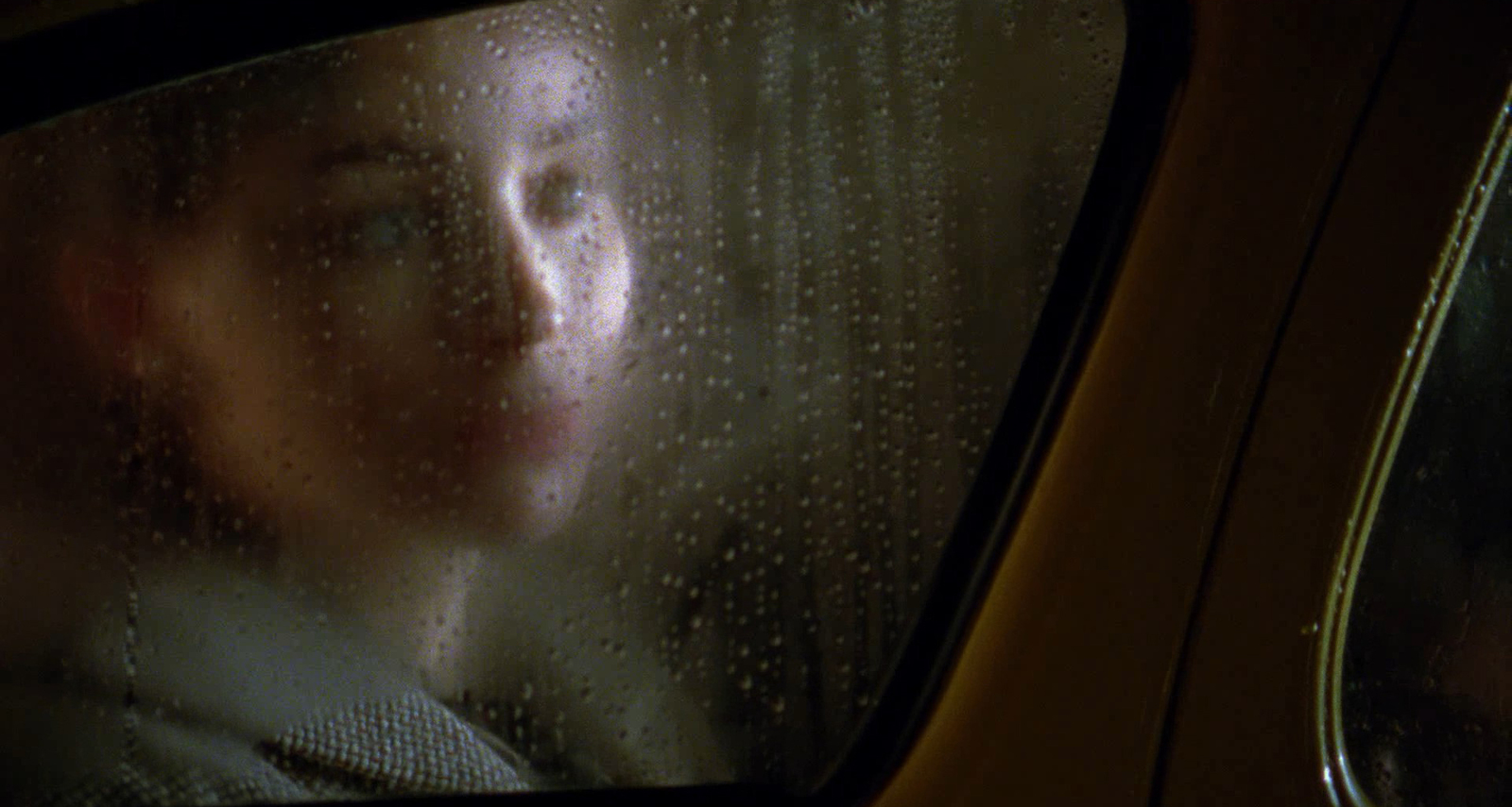 a woman looking out of a car window in the rain