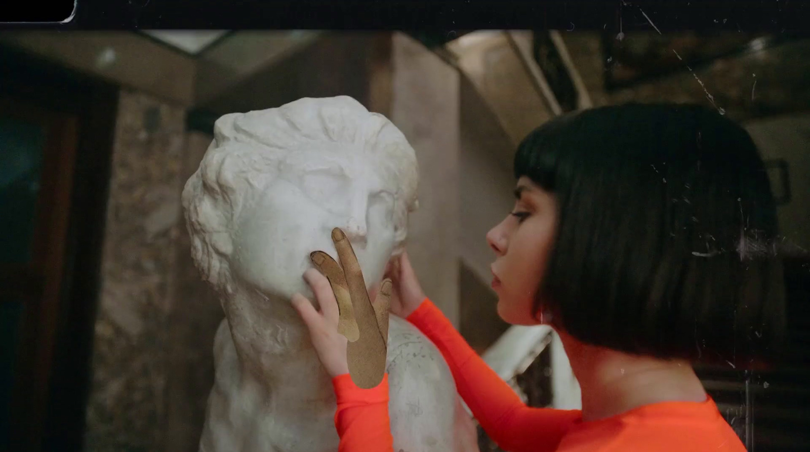 a woman in an orange dress touching a white statue