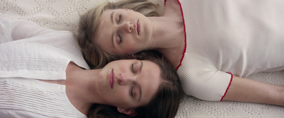 a couple of women laying next to each other on a bed