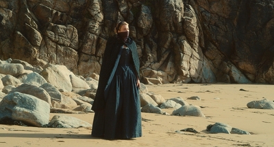 a woman in a blue dress standing on a beach