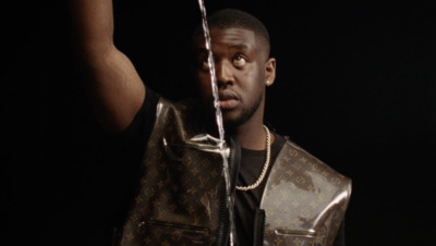 a man in a brown jacket holding a brown louis vuitton bag