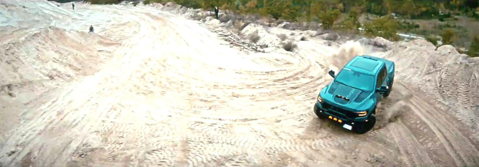 a blue truck driving down a snow covered road