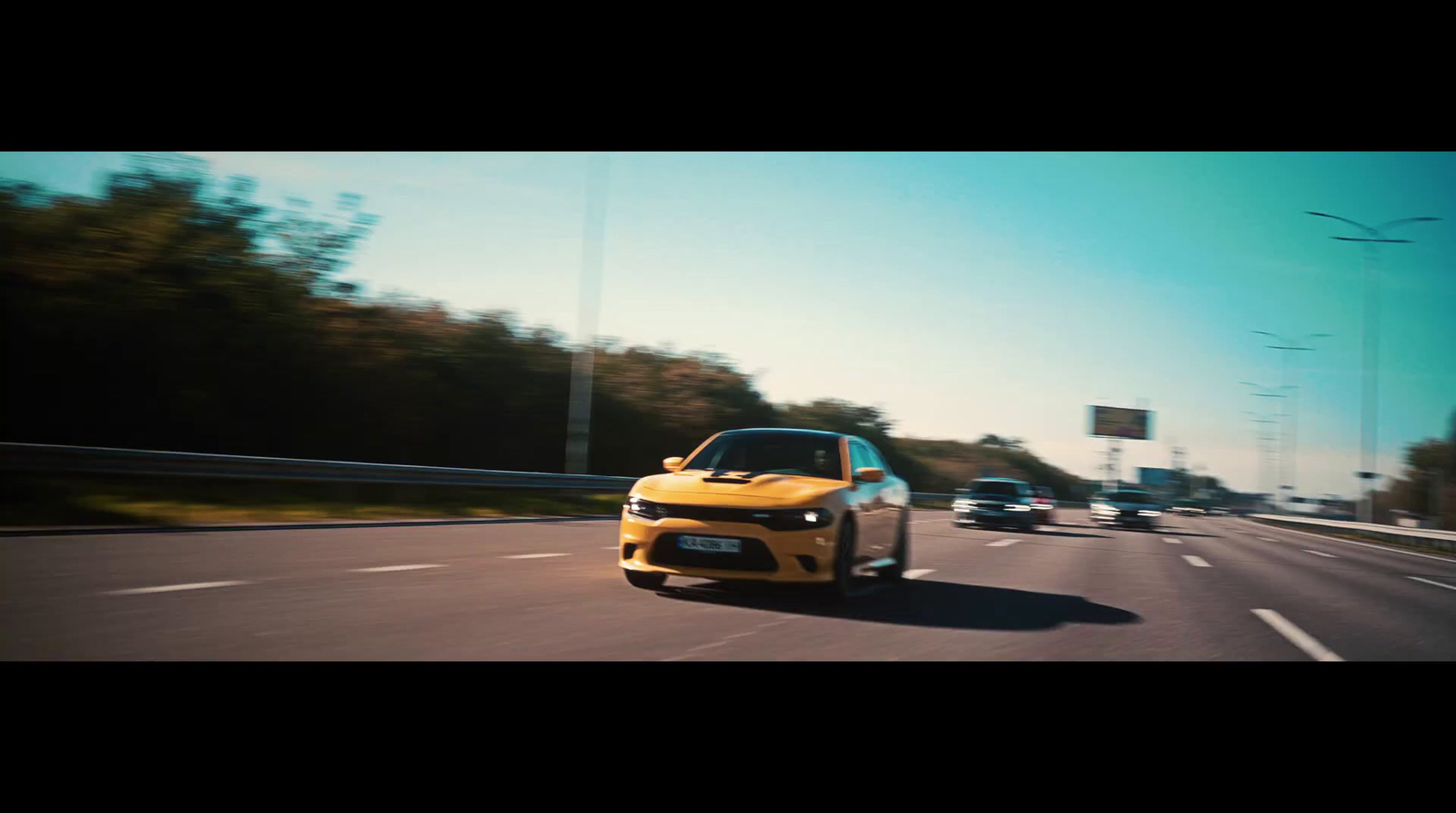 a yellow car driving down a highway next to a forest