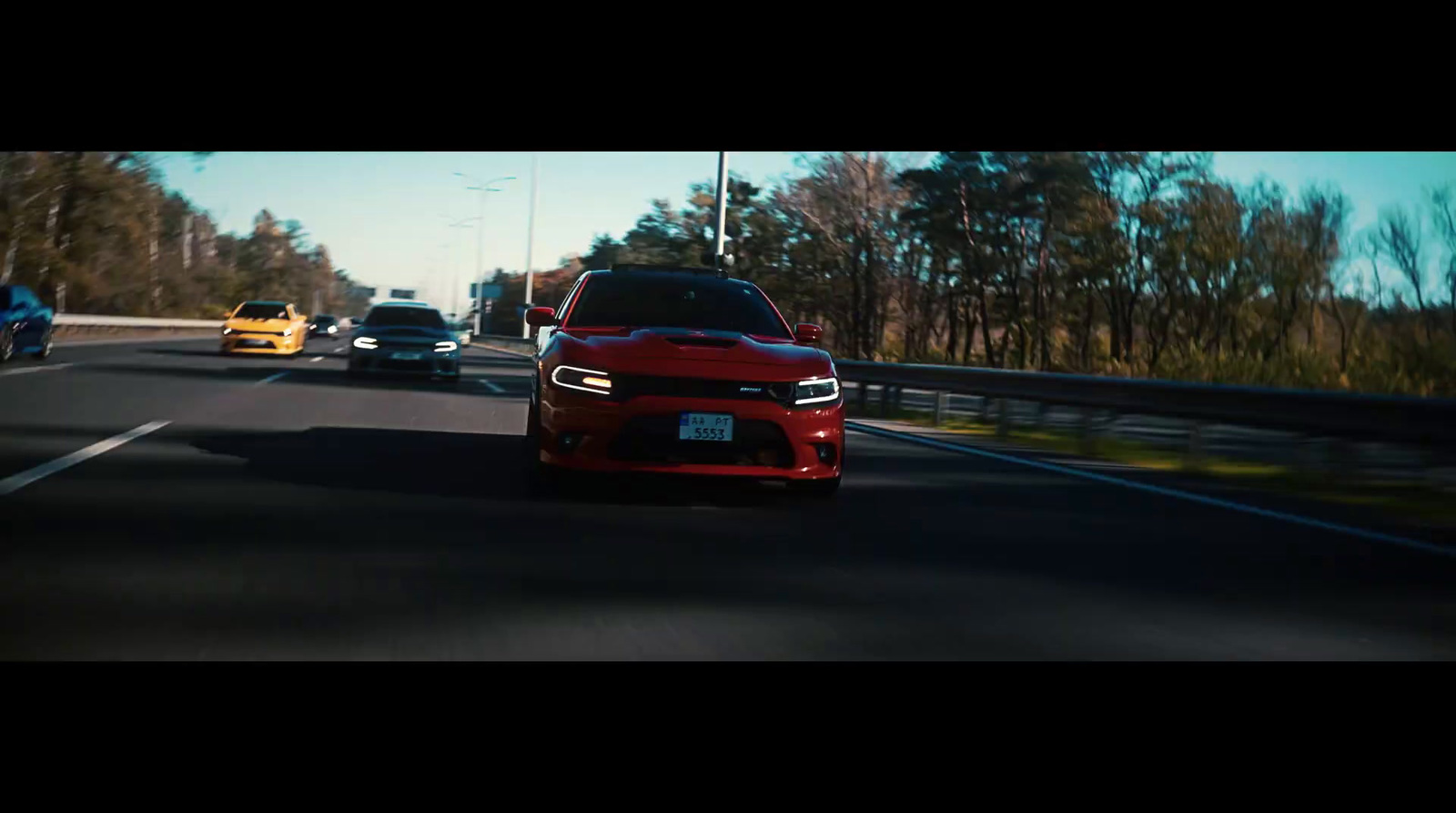 a red car driving down a highway next to a forest