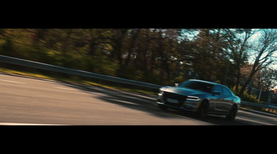 a car driving down a road next to a forest