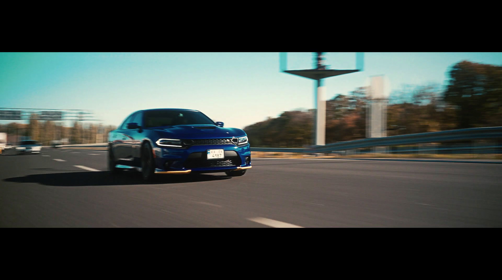 a blue car driving down a road next to a tall building