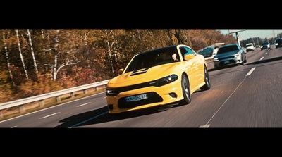 a yellow car driving down a highway next to a forest