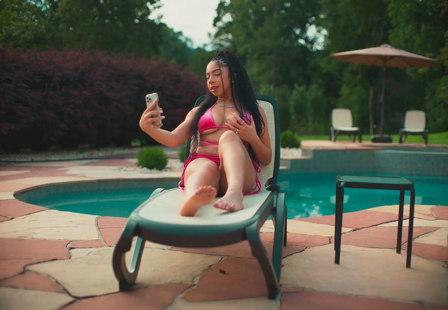 a woman in a pink bikini sitting on a chair next to a pool