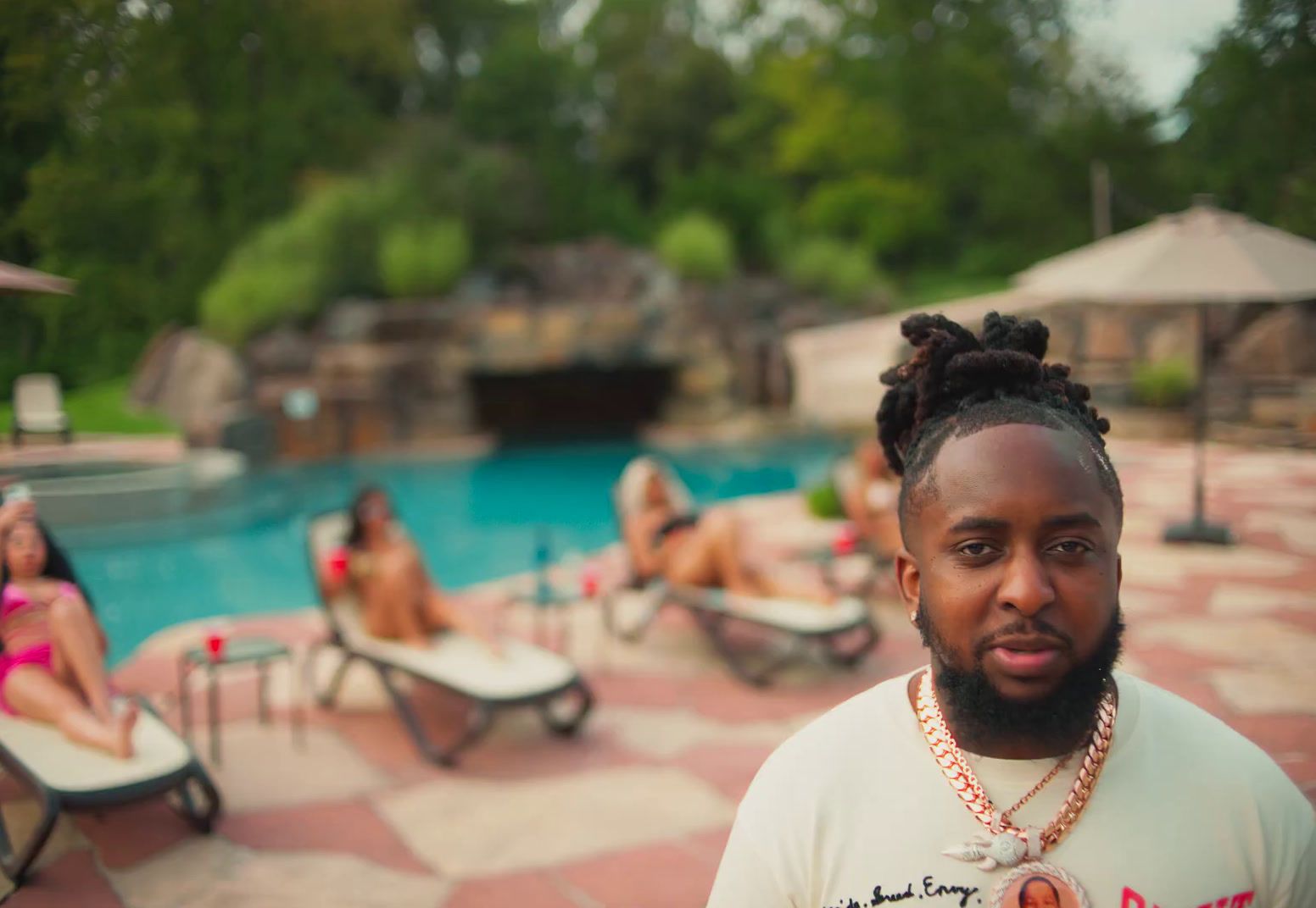 a man with dreadlocks standing in front of a pool