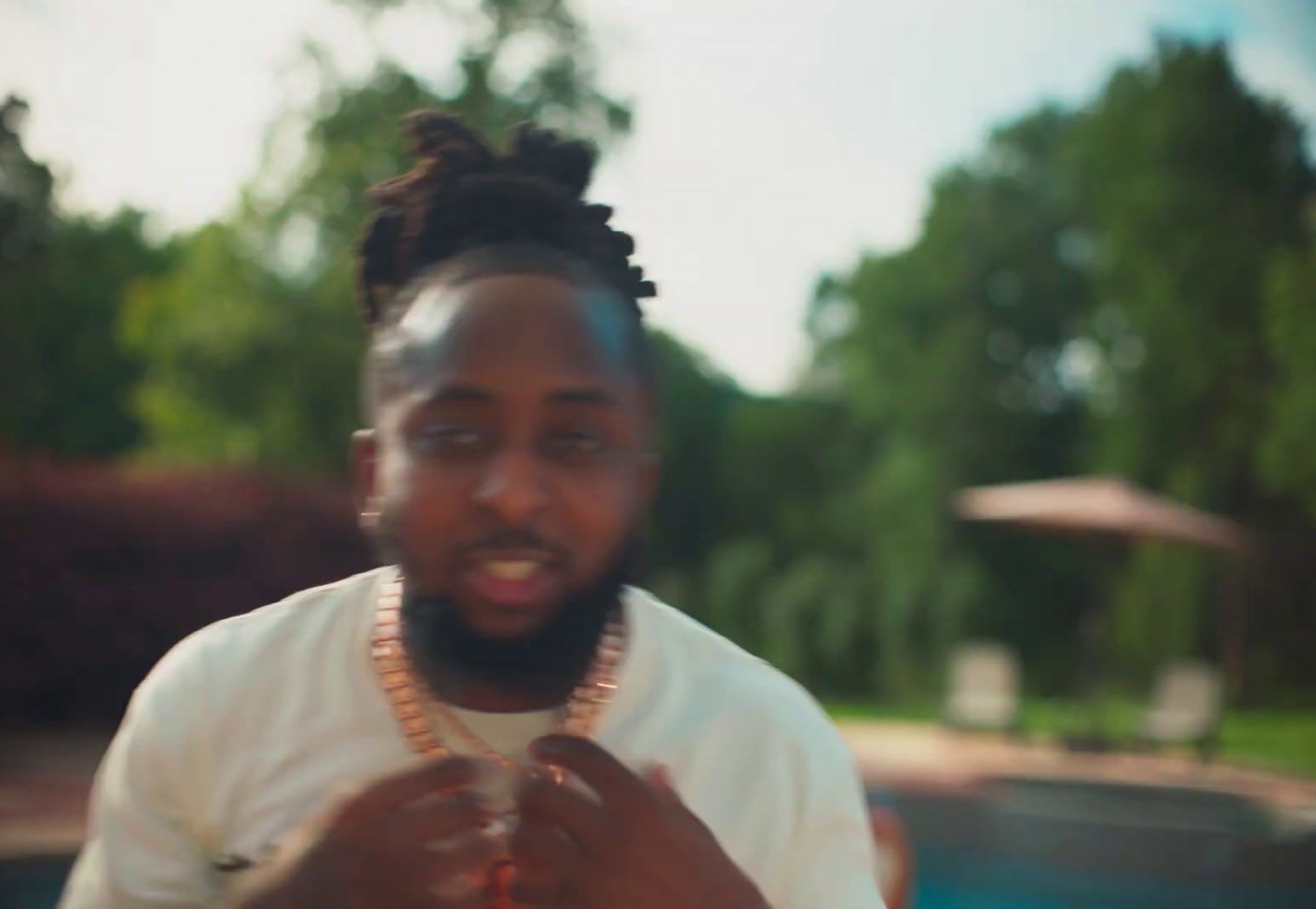 a man standing in front of a pool wearing a necklace