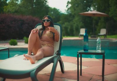 a woman sitting in a chair next to a pool