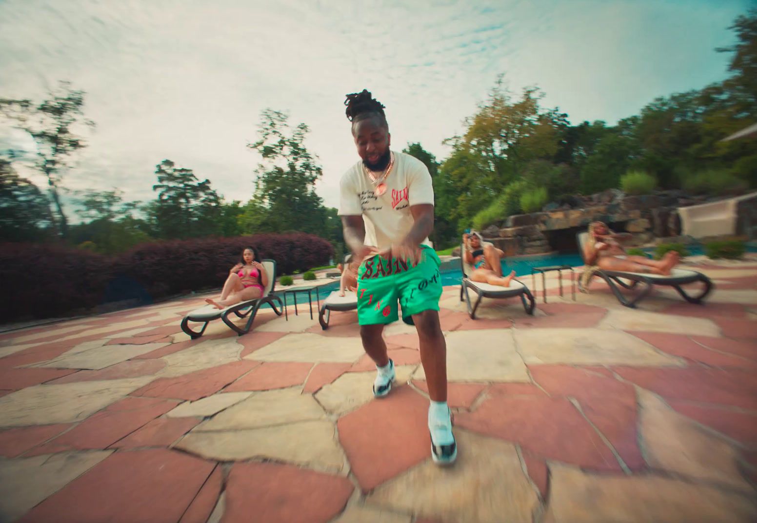 a man in a white shirt and green shorts playing with a frisbee