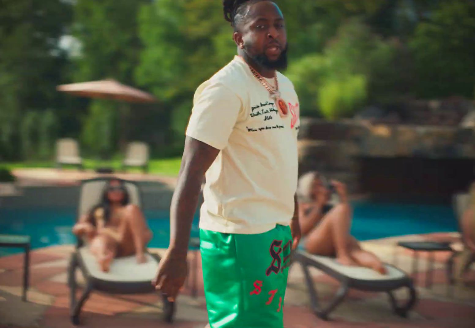 a man in a white shirt and green shorts standing in front of a pool