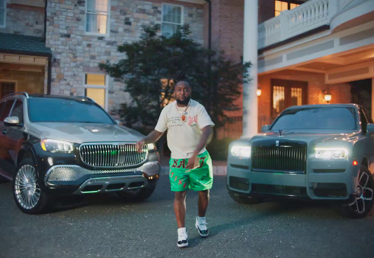 a man standing next to two cars in front of a building