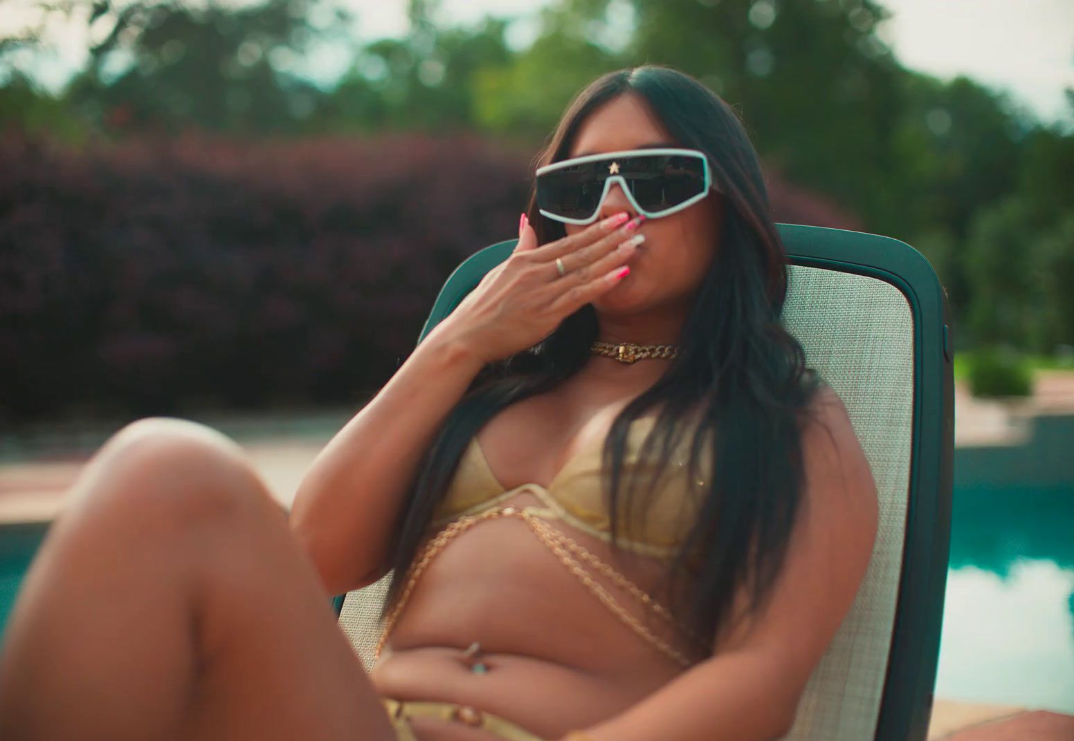 a woman in a bikini sitting in a chair next to a pool