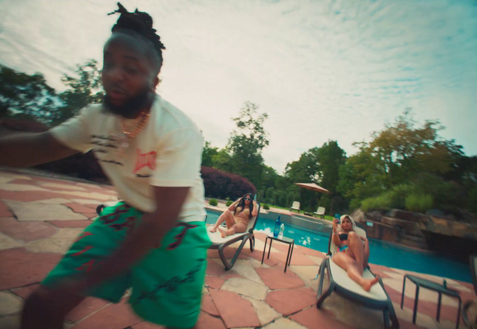 a man in a white t - shirt is dancing by a pool