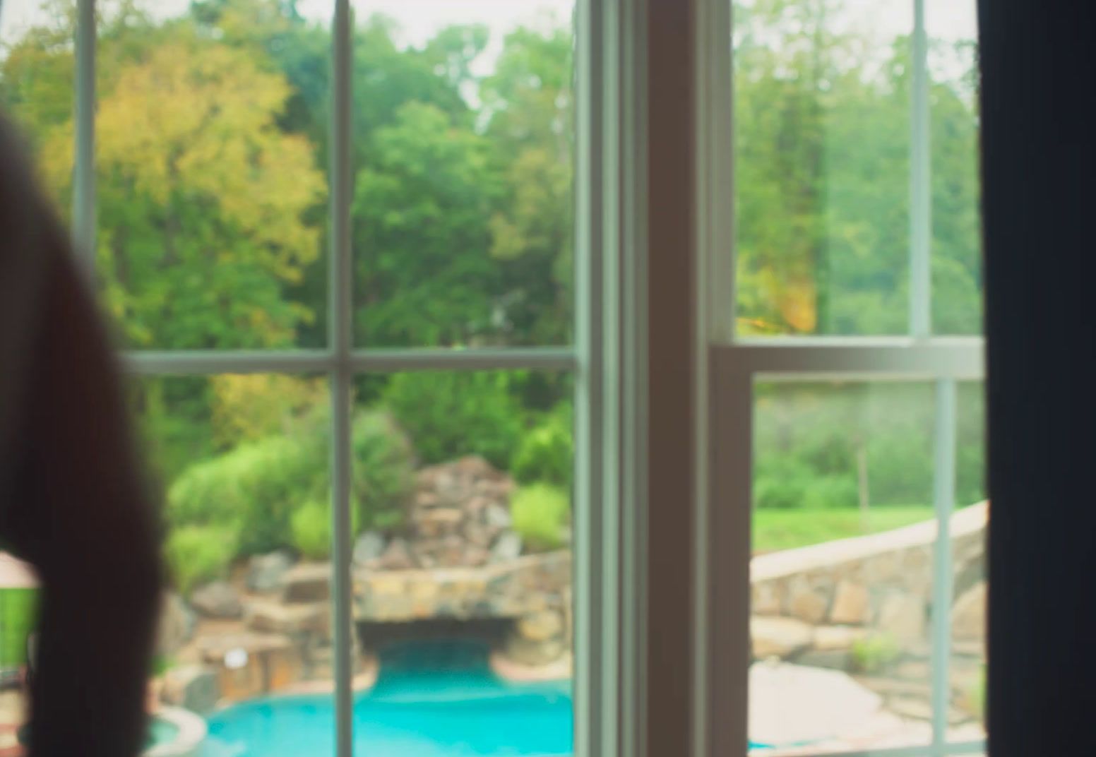 a woman looking out a window at a pool