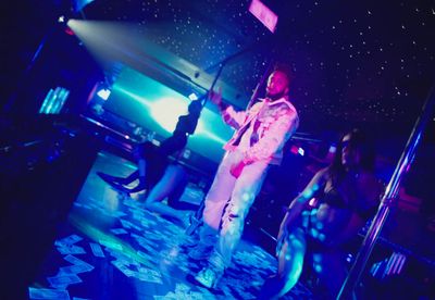 a man in a white suit standing on a stage