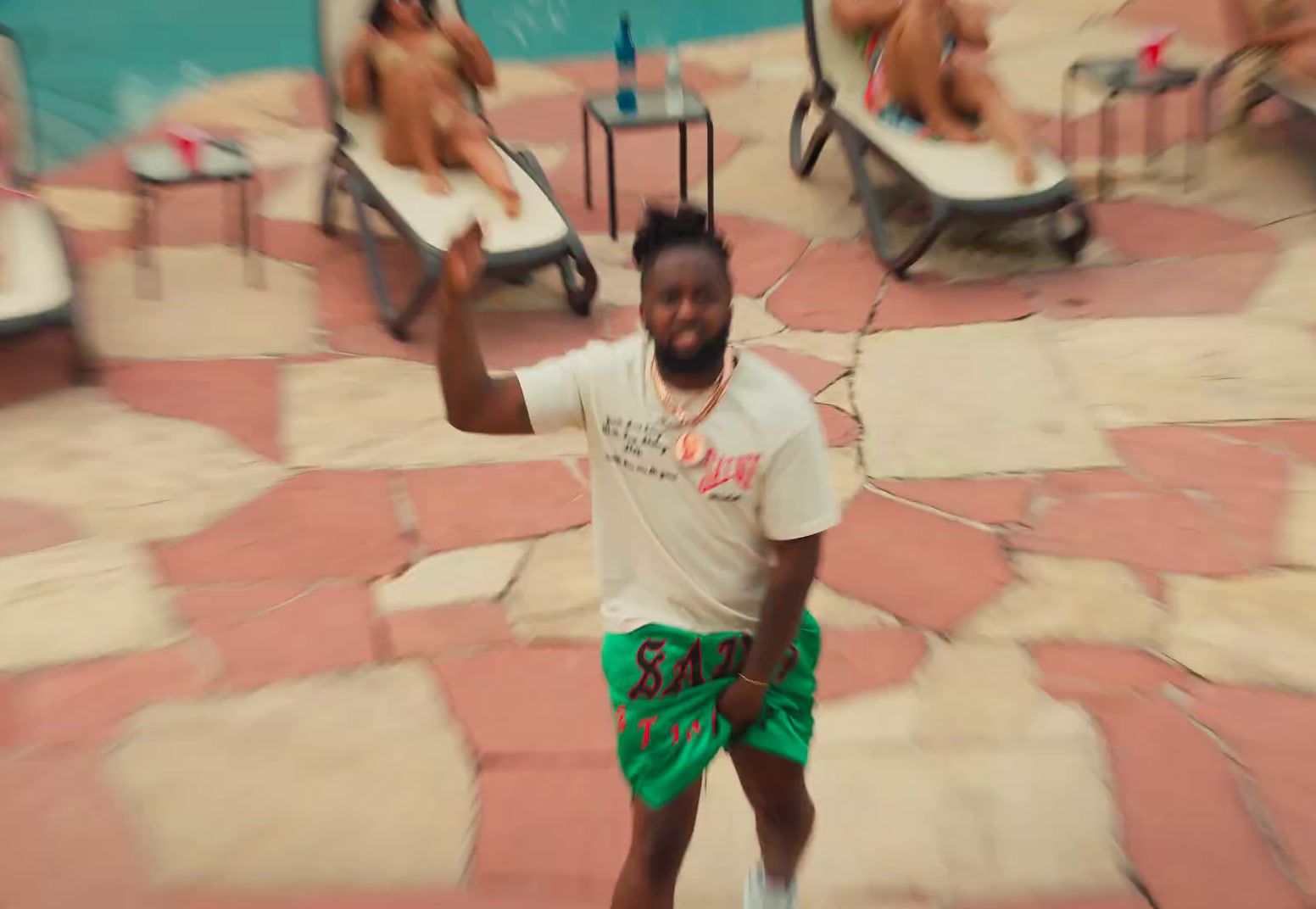 a man in a white shirt and green shorts playing with a frisbee