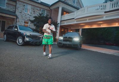 a man in green shorts standing in front of a black car