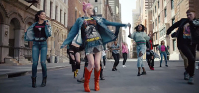 a group of people walking down a street next to tall buildings