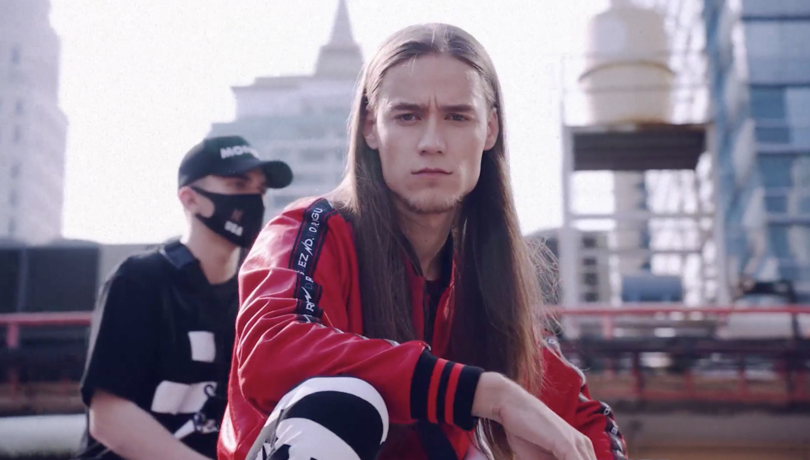 a man with long hair sitting on a skateboard