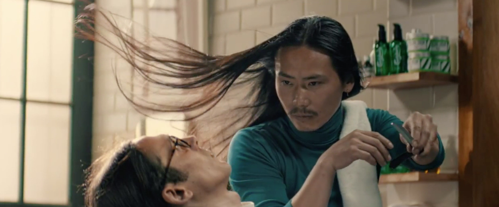 a woman blow drying a man's hair in a kitchen