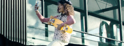 a woman in a polka dot shirt and white pants holding a skateboard