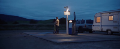 a man standing at a gas pump at night