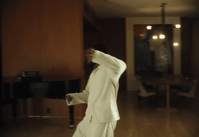 a man in a white suit dancing in a living room