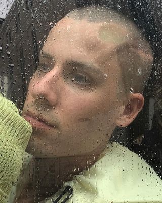 a man looking out of a window in the rain