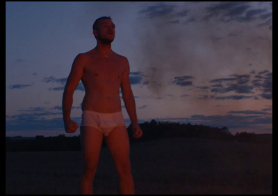 a man in a white underwear standing in a field