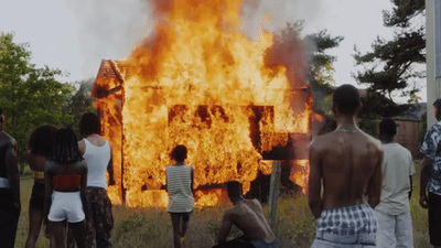 a group of people standing around a burning house