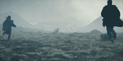 a group of people walking across a grass covered field