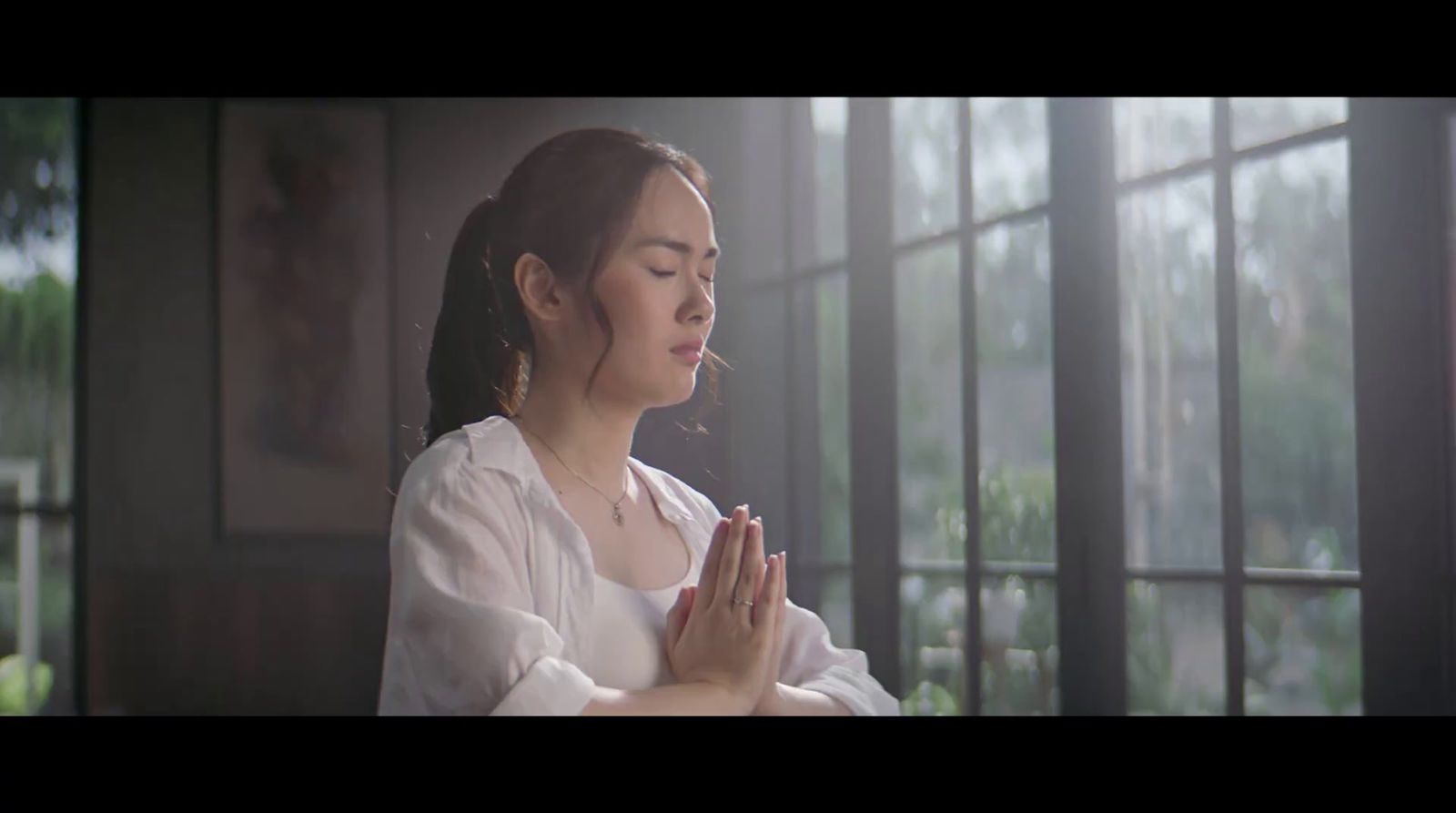 a woman sitting in front of a window praying