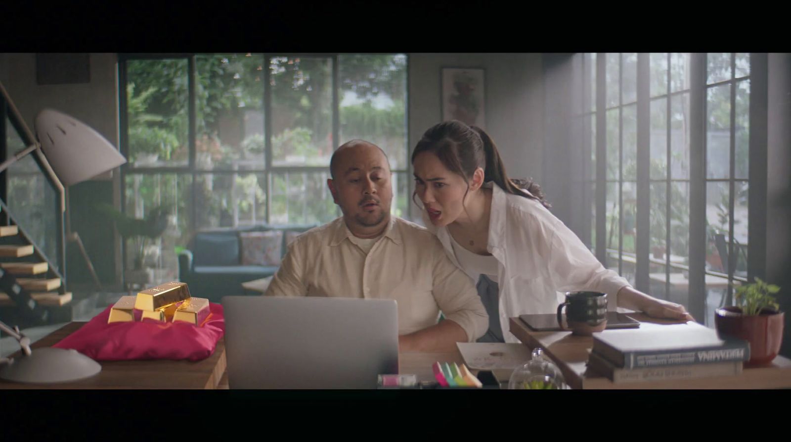 a man and a woman sitting at a desk looking at a laptop