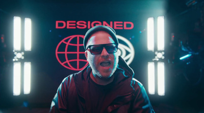 a man wearing sunglasses and a hoodie in front of a neon sign