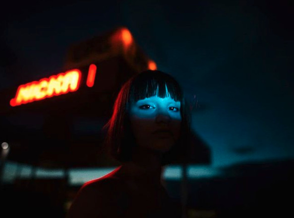 a woman standing in front of a neon sign