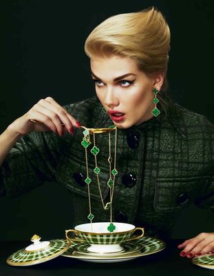 a woman is holding a necklace over a teacup