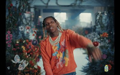 a man in an orange shirt is dancing in front of flowers