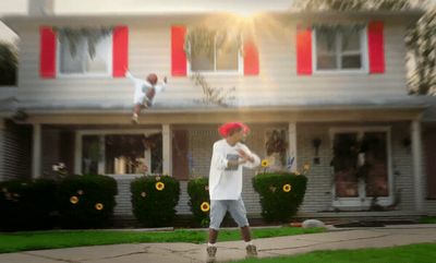 a boy is jumping in the air in front of a house