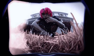 a man with pink hair sitting in the grass